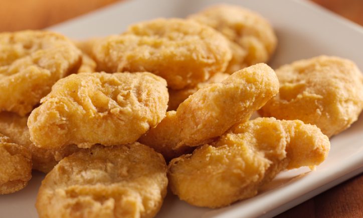 photo shot up close of crispy golden chicken nuggets piled up on a plate